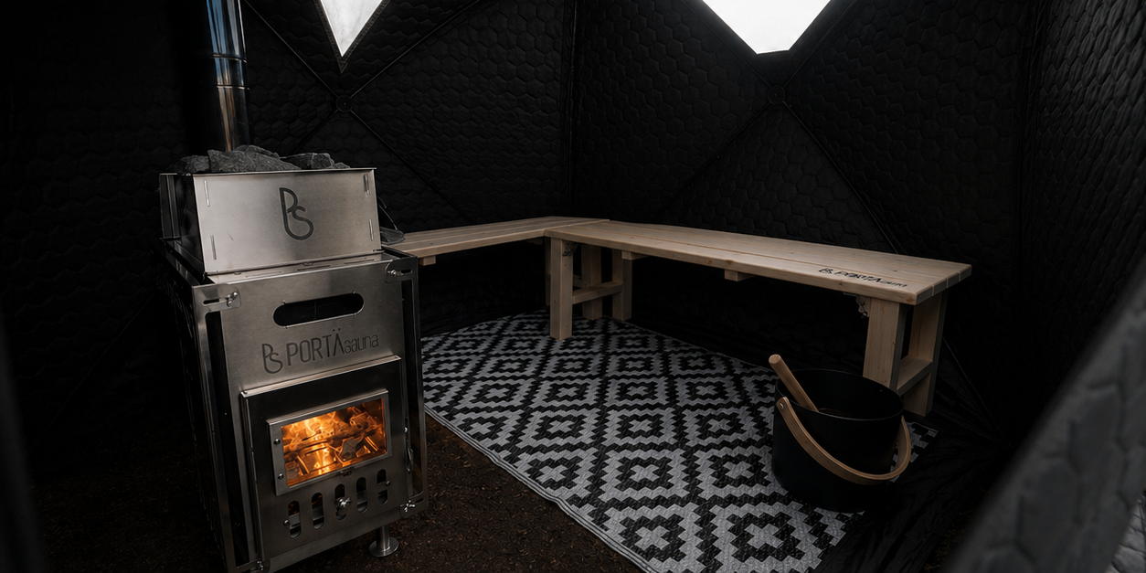 Inside the PortaSauna Kabin: wood-burning stove, cedar bench seating and warm low light.